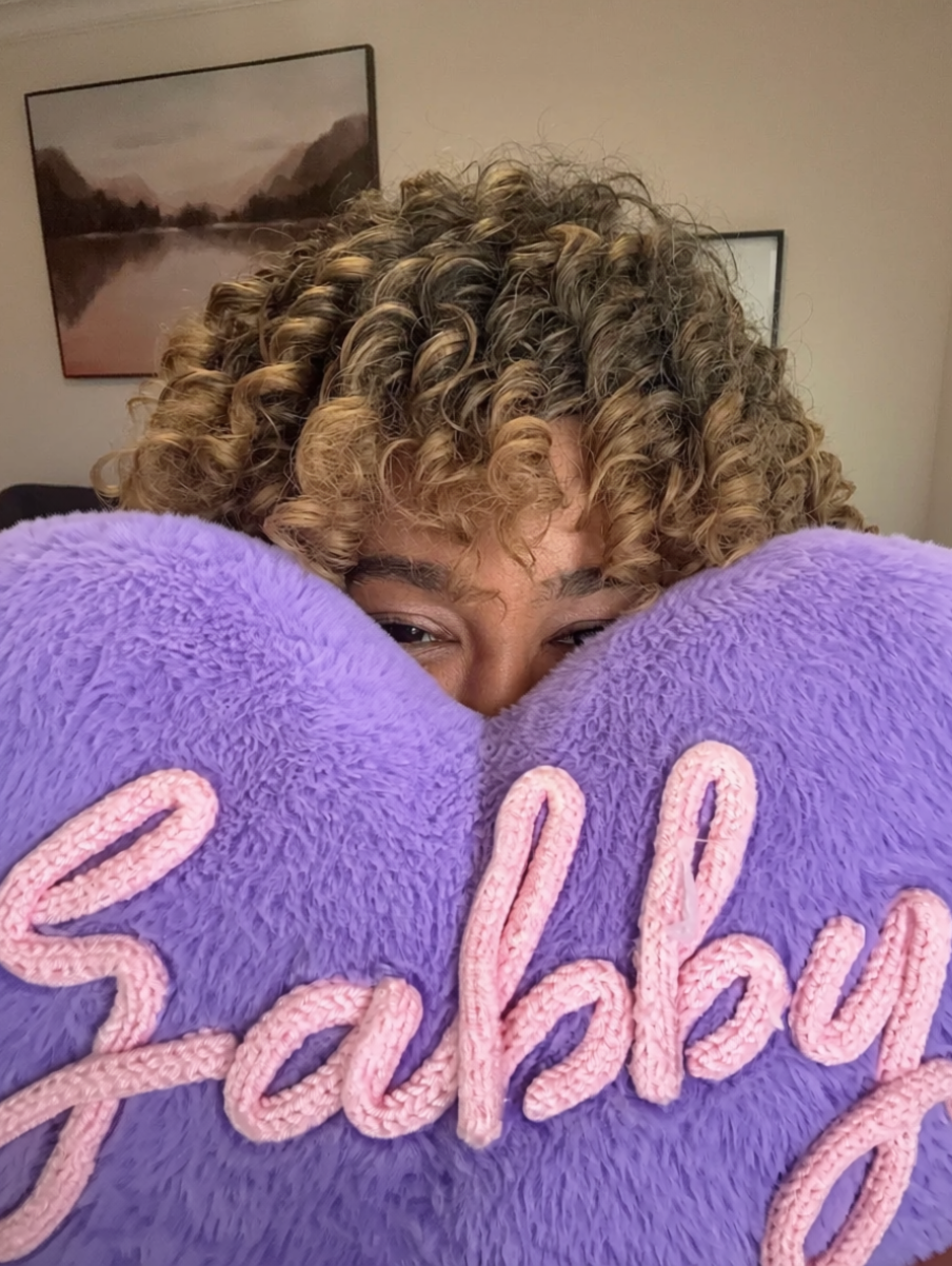 Gabrie'le Eato holding a purple pillow with the text Gabby